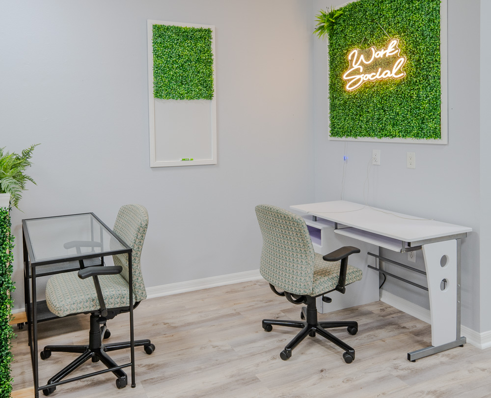 Private office with two desks and the Work Social neon sign